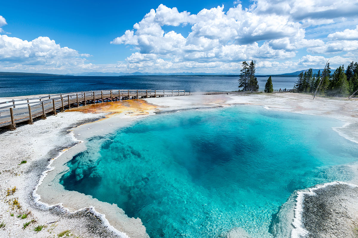 A crystal clear hot spring pool near a boardwalk in Yellowstone National Park