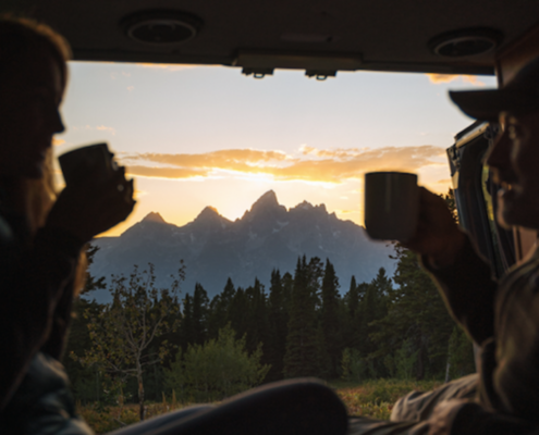Man and Woman Enjoying Drinks and Grand Teton View in a Moterra Sprinter Campervan Rental in Jackson Hole, Wyoming