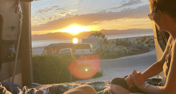 Man and Woman Enjoying Sunset Over Mountains and Lake in Moterra Campervan Rental for Road Trips