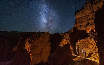 Person with Light Against Canyon Wall on Starry Night in Bryce Canyon National Park, Utah